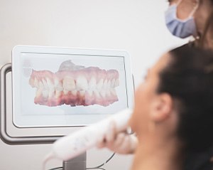 Dental assistant taking digital impressions of patient's teeth