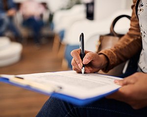 Woman filling out dental insurance form in lobby