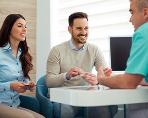 Dentist and couple talking in dental office