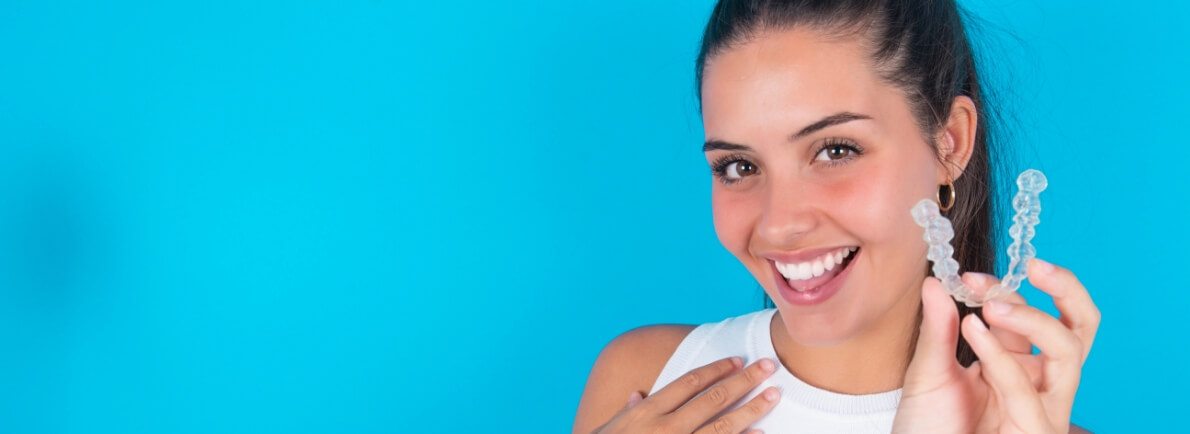 woman with dark hair holding invisalign