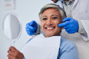 Dentist pointing to patient’s teeth as she smiles